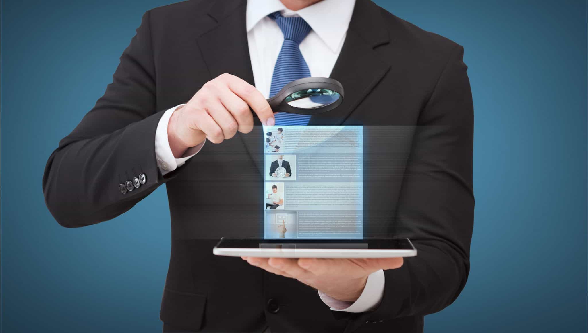 Businessman using magnifying glass to review digital job details for signs of a recruitment scam.
