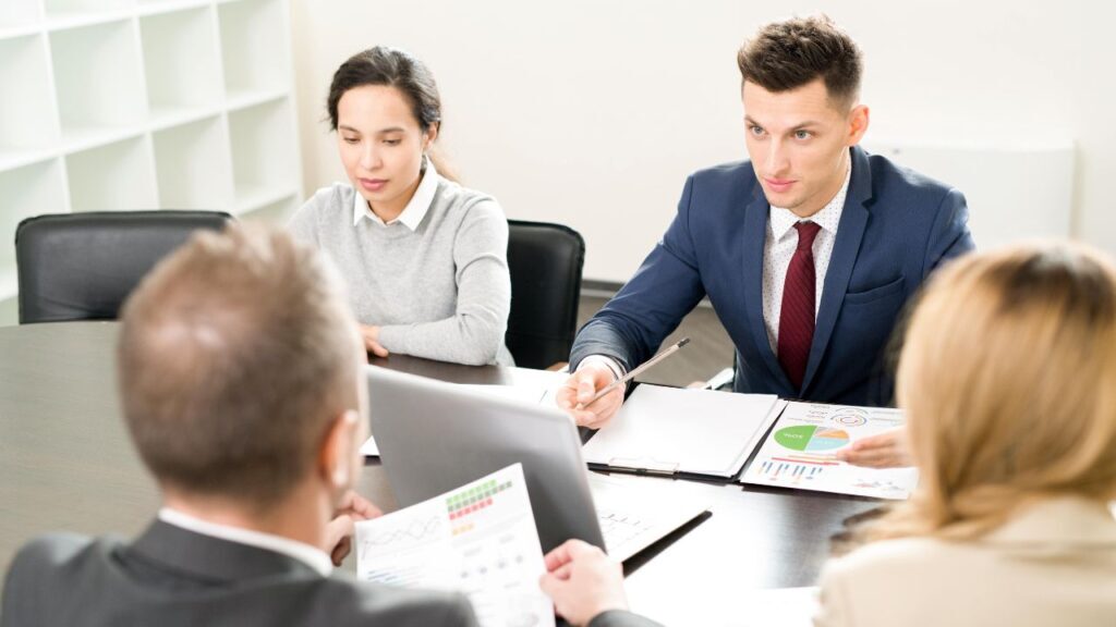Business professionals discussing charts and data during a meeting at an executive search firm.