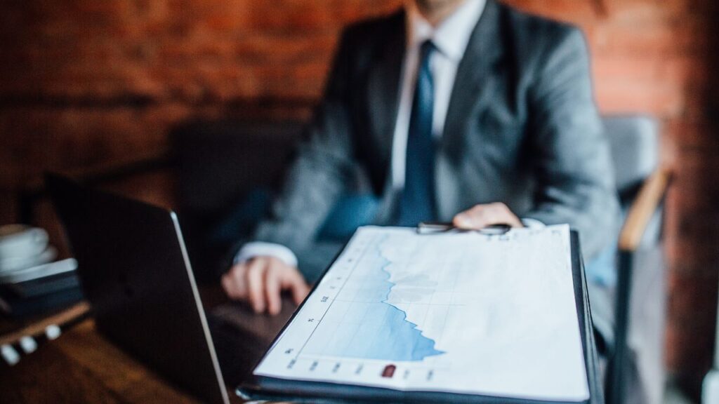 Businessman holding a clipboard with a graph in a meeting, representing data analysis at an executive search firm.