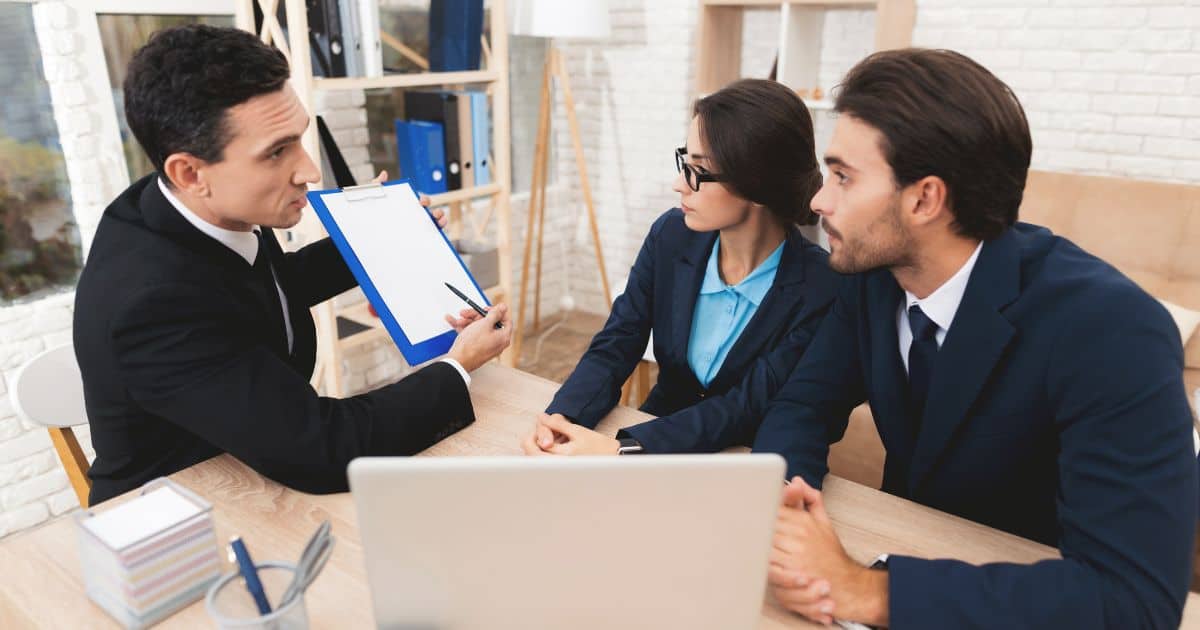 A team of Education Executive Search Consultants presents a document to clients during an office meeting.