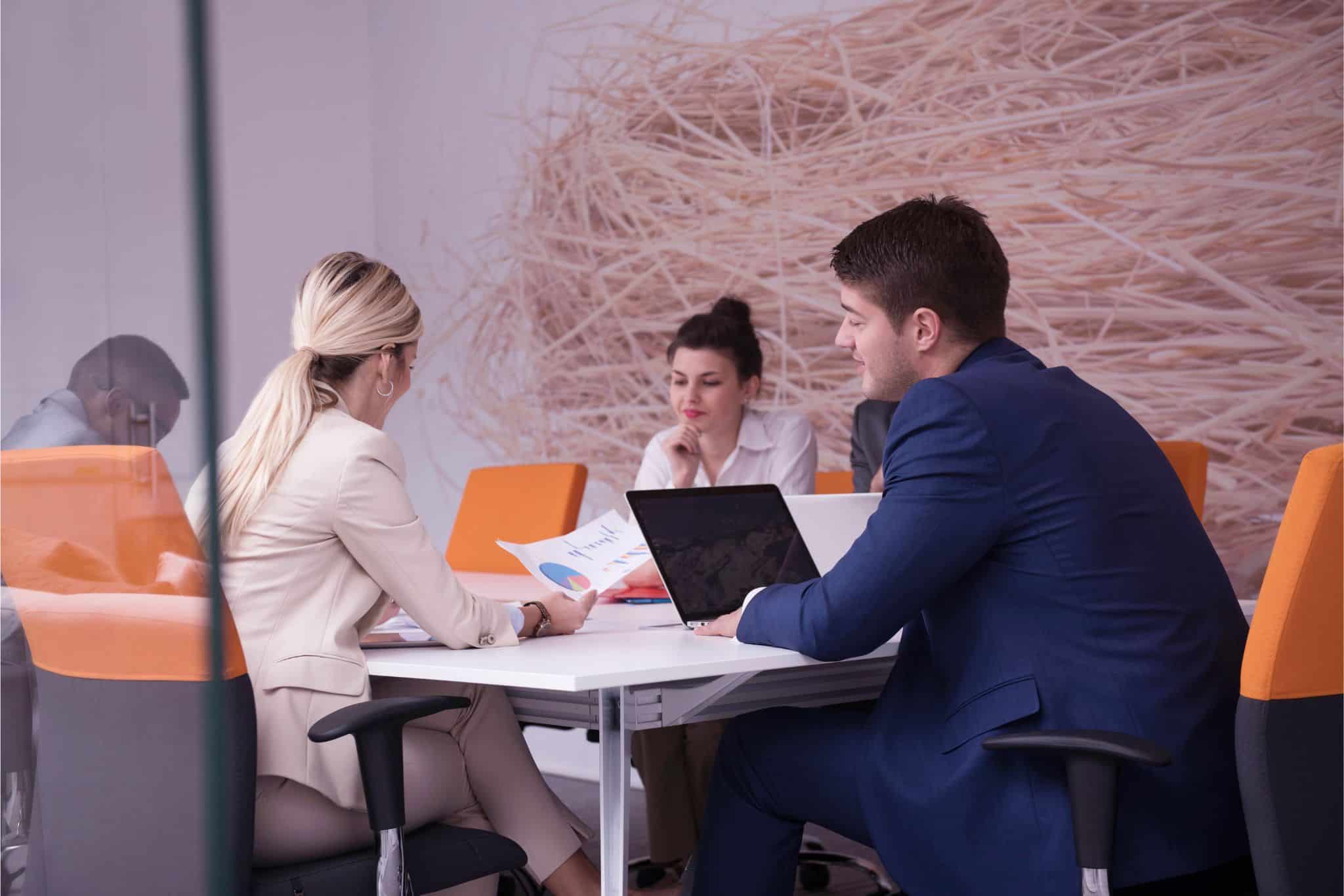 Team meeting with laptops and charts in modern room, representing life science & healthcare executive search collaboration.