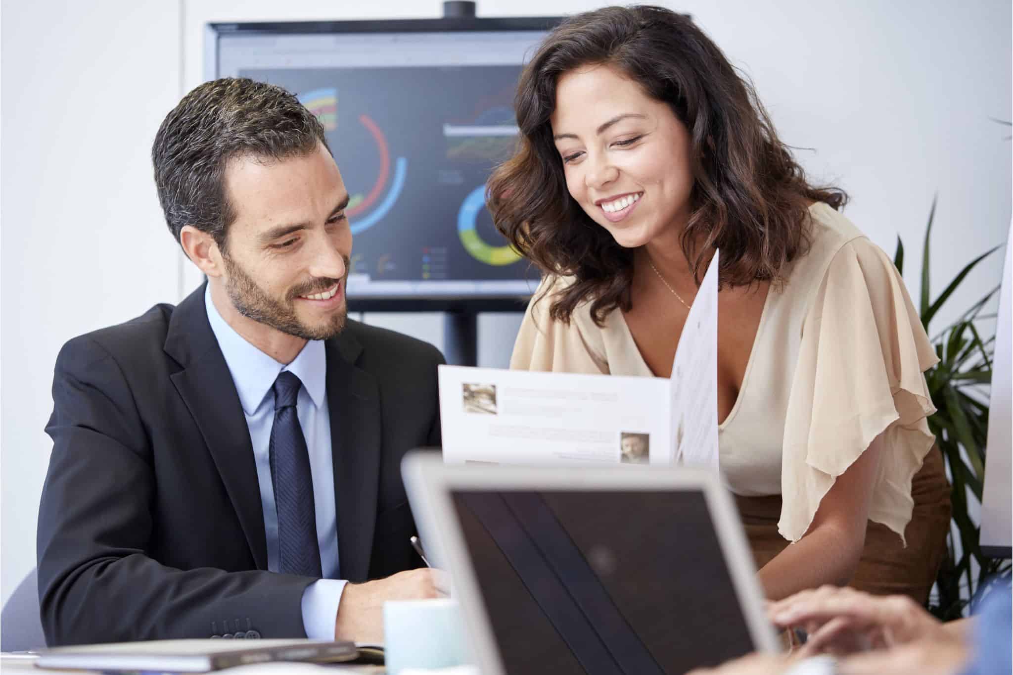 Smiling professionals discussing financial reports during executive hiring process in an office setting