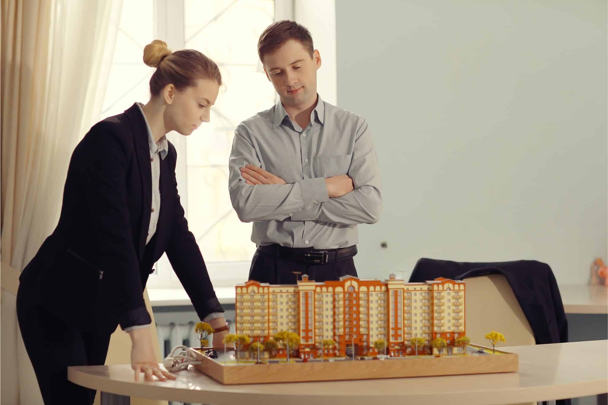 Professionals reviewing a real estate construction model, showcasing executive search skills in a modern office.