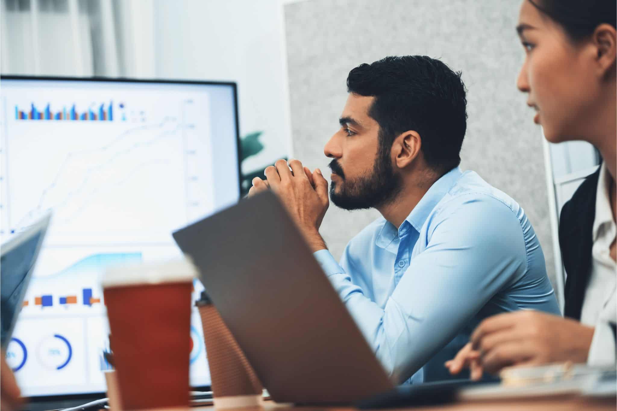 Team analyzing data charts on screen and laptops, representing life science & healthcare executive search strategy.