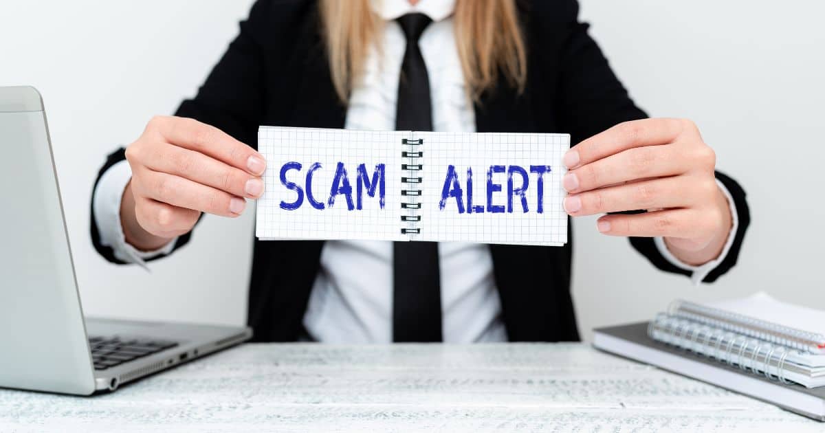 Person holding paper with scam alert text to warn about common signs of recruitment scams and fraud.