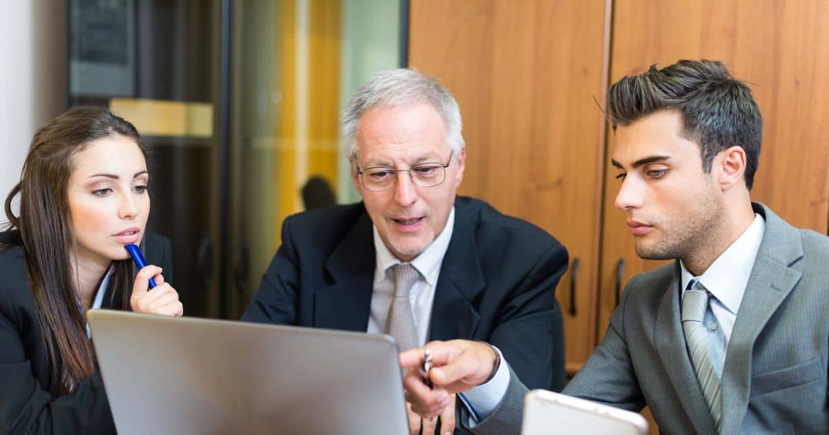 A diverse team reviewing a strategy on a laptop, guided by Telecom Executive Search Consultants advice.