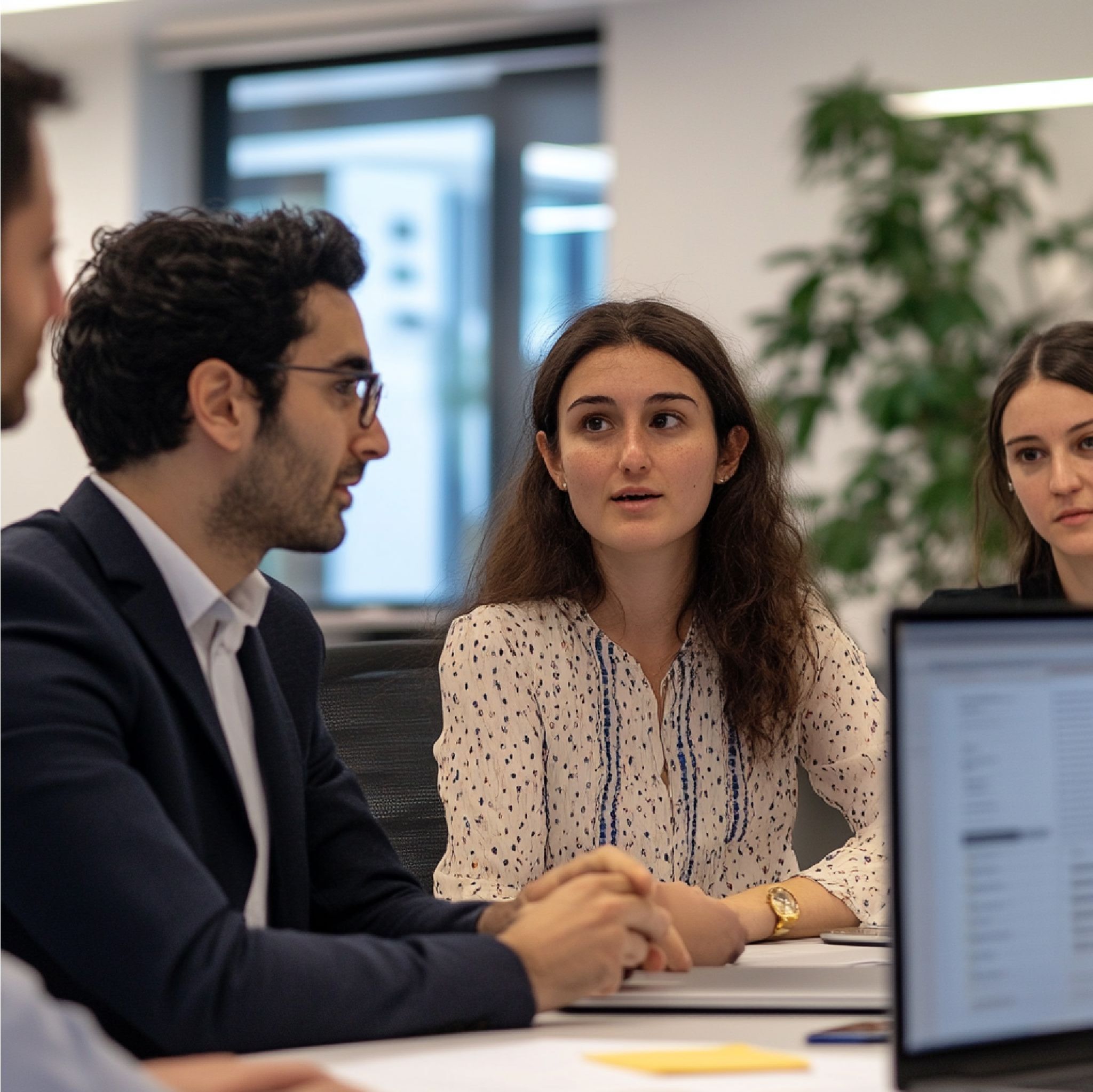 Three development executive search consultants in a serious, collaborative meeting at a conference table.