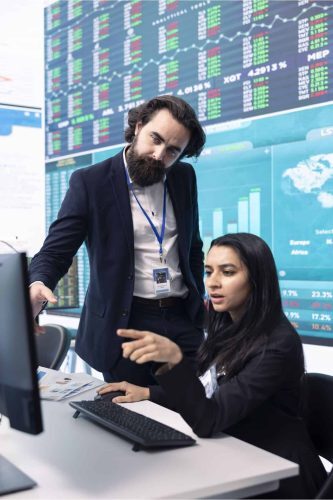 Financial Executive Search for Top Leaders in Investment & Market Strategy Man and woman in finance discussing market data on monitor, depicting financial executive recruitment